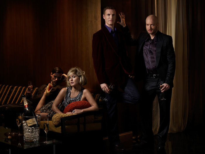 Four people in evening dress in a wood-panelled bar, Moet on ice in the foreground.